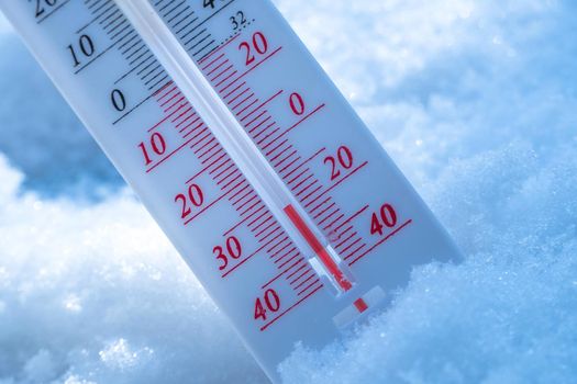 The thermometer lies on the snow in winter showing a negative temperature. Meteorological conditions in a harsh climate in winter with low air and ambient temperatures.Freeze in wintertime