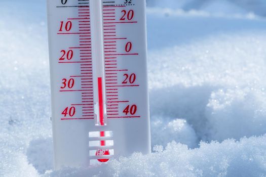 The thermometer lies on the snow in winter showing a negative temperature. Meteorological conditions in a harsh climate in winter with low air and ambient temperatures.Freeze in wintertime