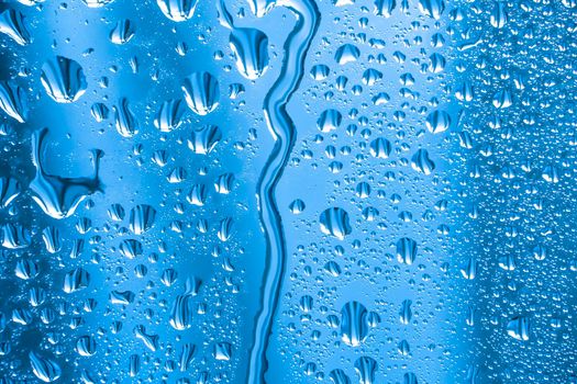 Abstract background ornament with water drops.Raindrops on the glass in rainy weather.The glittering, shiny surface of water on glass.Water drops in the form of balls or spheres.Blue raindrops