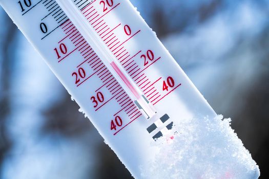 The thermometer lies on the snow in winter showing a negative temperature. Meteorological conditions in a harsh climate in winter with low air and ambient temperatures.Freeze in wintertime