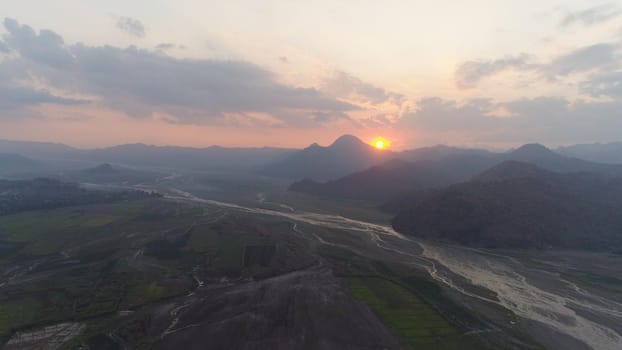 Aerial view sunset in mountain valley along which the river flows, surrounded by mountains covered with forest. Pinatubo, Cordillera region. Luzon, Philippines. Mountain landscape.