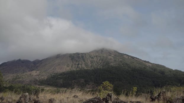 Volcano, mountain covered forest, sky with clouds, traces of lava on the ground. Mount Batur Volcano in Kintamani. Mountain landscape, Bali. Travel concept.