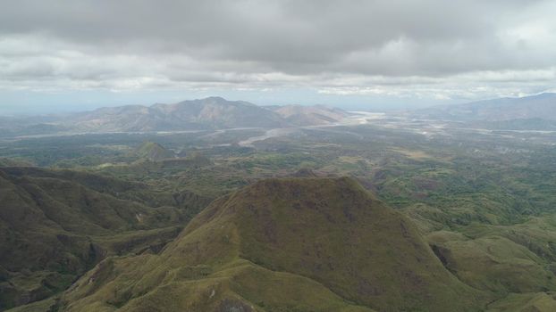 Aerial view of mountains covered with green vegetation, trees in vicinity volcano Pinatubo. Slopes of mountains, sky and clouds. Cordillera region. Luzon, Philippines.