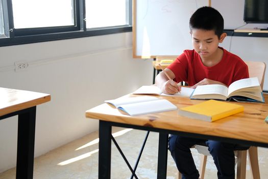 asian boy student studying writing notes doing homework in library. learning education at school