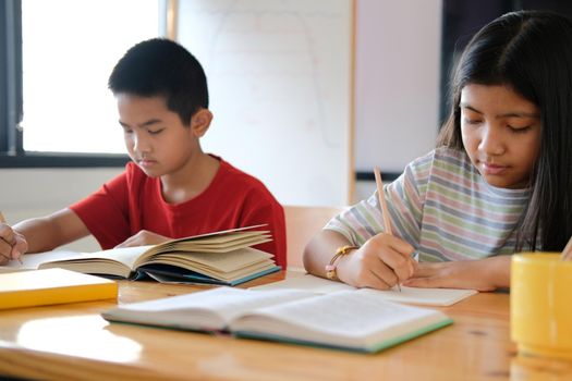 asian boy girl student studying writing notes doing homework in library. learning education at school