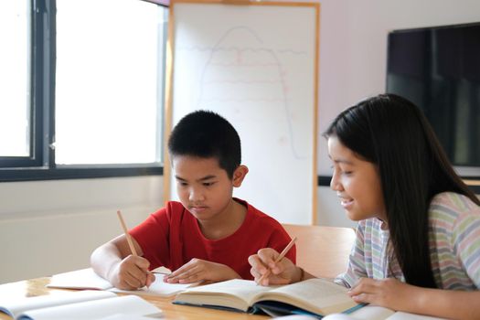 asian boy girl student studying writing notes doing homework in library. learning education at school