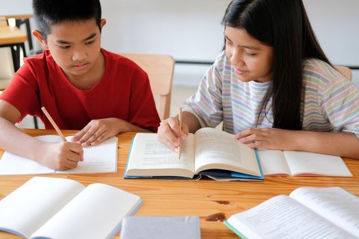 asian boy girl student studying writing notes doing homework in library. learning education at school