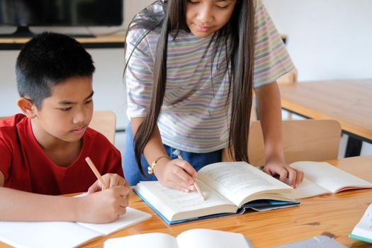 asian boy girl student studying writing notes doing homework in library. learning education at school