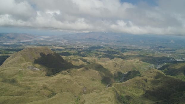 Aerial view of mountains covered with green vegetation, valley, trees in vicinity volcano Pinatubo. Slopes of mountains, sky and clouds. Cordillera region. Luzon, Philippines.