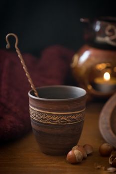 Dark background with a hot drink in a ceramic Cup and the scattered nuts hazelnuts on a wooden surface.