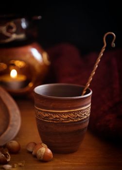 Dark background with a hot drink in a ceramic Cup and the scattered nuts hazelnuts on a wooden surface.