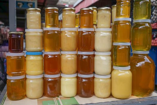 honey of different color in banks on a counter for sale.