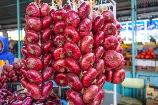 Products of the Yalta market, red onions in long bundles on the counter for sale.