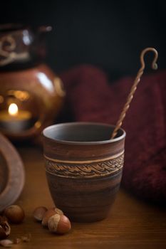 Dark background with a hot drink in a ceramic Cup and the scattered nuts hazelnuts on a wooden surface.