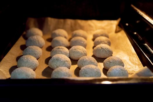 Oven with cookies on a baking sheet on parchment.