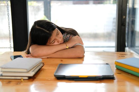 tired exhausted asian girl student sleeping after studying hard exam in library
