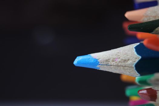 Close-up view of bright colored multicolor pencils on black background