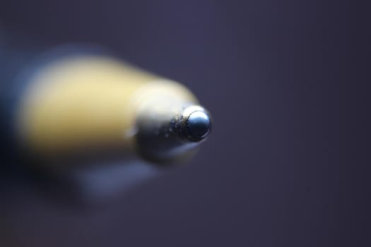 Macro photo of ballpoint pen tip with dark grey background. Extreme macro image of metal ballpoint pen on grey background.