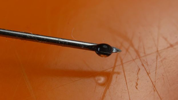 Close-up of vaccine drop on syringe needle. Water drop falling from the syringe needle