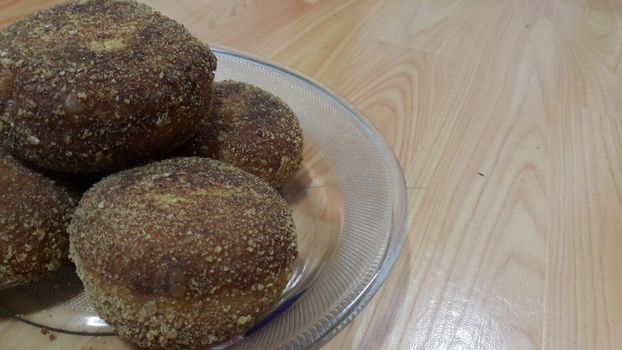 Closeup perspective view of fried pizza bomb or pizza balls served in a glass plate over wooden floor. Pizza bombs are delicious and tasty altered form of pizza.