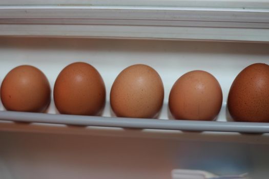 Selective focus of chicken eggs in egg rag on shelf on the fridge door of refrigerator