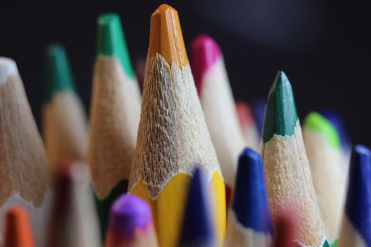 Close-up view of bright colored multicolor pencils on black background