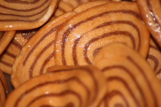 Closeup view with selective focus of a large number of round cookies with coconut filling lines.