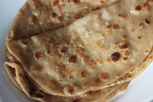 Closeup view of hand made plain bread in oil called paratha roti. Paratha is popular in India, Pakistan and other South Asian countries. Texture for bread.