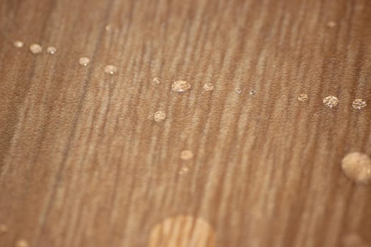 Closeup selective focus view of water drops on wooden floor. Abstract raindrops pattern on wooden board