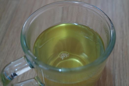 Glass cup having brewed fragrant green tea or qehwa or qahwa on the wooden floor. It is served with sugar or honey and nuts