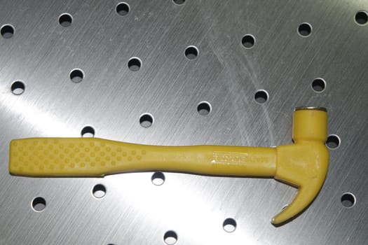 Selective focused, closeup view of toy hammer made from plastic placed on metal background