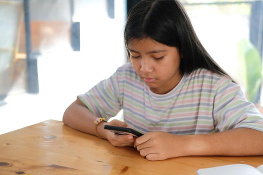 asian girl student using social media online app on smart mobile phone in library