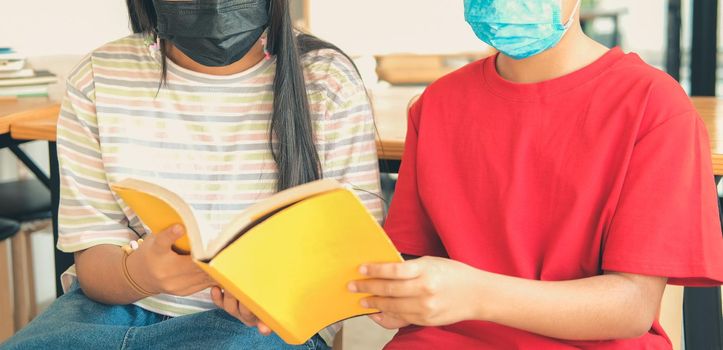 asian boy girl student wearing face mask studying reading book in library. learning education at school