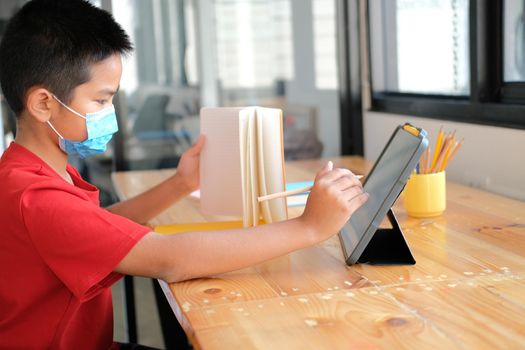 asian boy student wearing face mask studying learning lesson online. remote meeting distance education at home