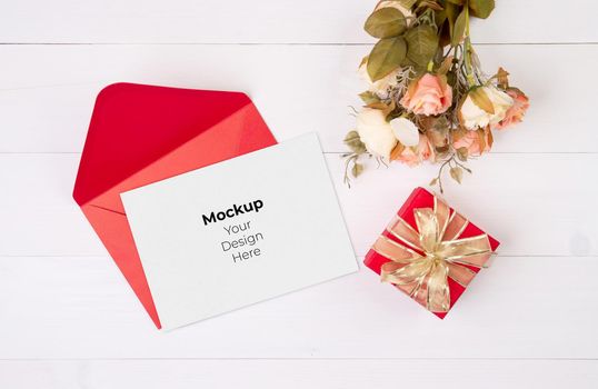 Valentine day, greeting card mockup and letter and flower on wooden table, postcard blank and gift box with romance on desk, present in anniversary and celebration, top view, holiday concept.