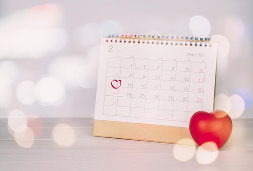 Calendar and heart shape with memo 14 February Valentine day on desk, reminder for surprise of love, romance and sweet, celebration and decoration, date and planner, nobody, top view, holiday concept.