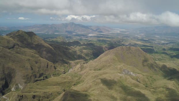 Aerial view of mountains covered with green vegetation, valley, trees in vicinity volcano Pinatubo. Slopes of mountains, sky and clouds. Cordillera region. Luzon, Philippines.