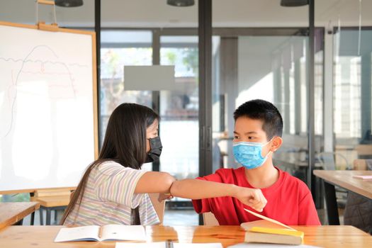 asian girl boy student friends wearing face mask greeting bumping elbow at school. new normal in covid pandemic outbreak