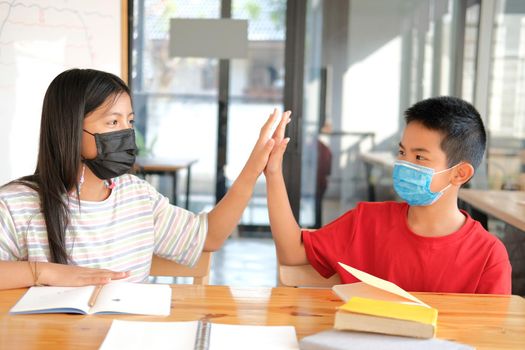 asian girl boy student friends wearing face mask giving high five at school