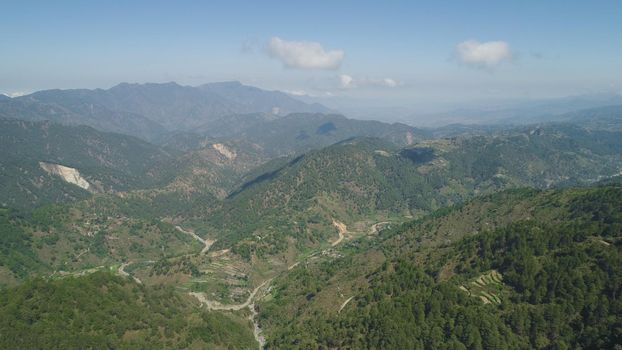 Aerial view of rice terraces and agricultural farm land on the slopes of mountains valley. Cultivation of agricultural products in mountain province. Mountains covered forest, trees. Cordillera region. Luzon, Philippines, Baguio province.