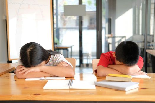 tired exhausted asian girl boy student sleeping after studying hard exam in library