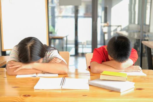 tired exhausted asian girl boy student sleeping after studying hard exam in library