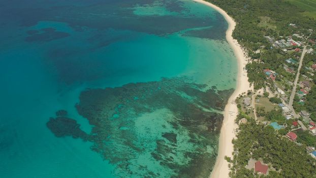Aerial view of beautiful tropical beach Saud with turquoise water in blue lagoon, Pagudpud, Philippines. Ocean coastline with sandy beach and palm trees. Tropical landscape in Asia.