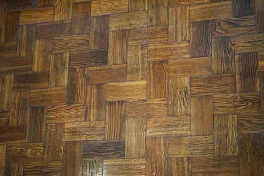 background of old wooden herringbone parquet flooring composed of boards of a different color.