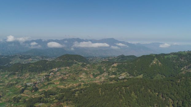 Aerial view of rice terraces and agricultural farm land on the slopes of mountains valley. Cultivation of agricultural products in mountain province. Mountains covered forest, trees. Cordillera region. Luzon, Philippines, Baguio province.