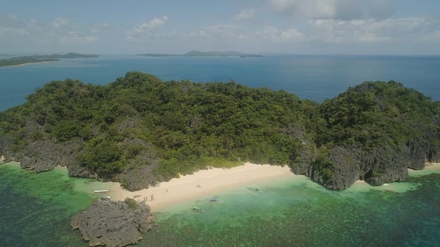 Aerial view Matukad island with sand beach and turquoise water in blue lagoon among coral reefs, Caramoan Islands, Philippines. Landscape with sea, tropical beach.