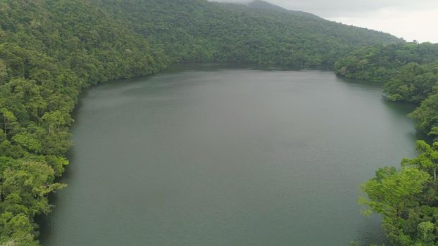 Aerial view of lake Bulusan in the mountains with green rain forest. Lake hidden in the jungle mountains near the volcano Bulusan. Tropical landscape with forest and lake. Philippines, Luzon