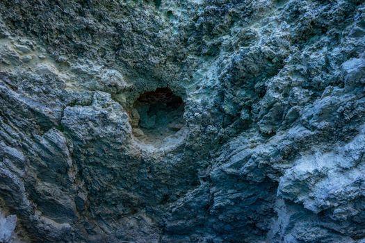 Background with a textured gray rock surface with a hole.