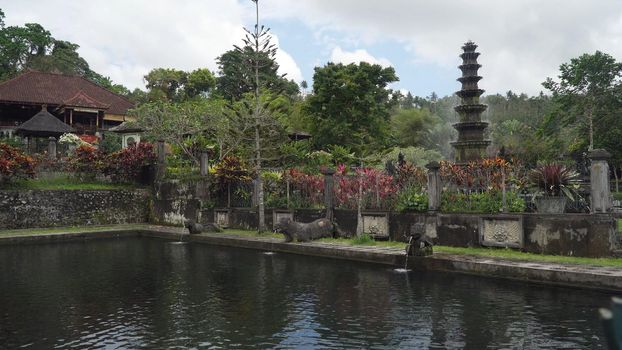 Hindu Balinese Water Palace Tirta Gangga with statues of the gods, fountains on Bali island, Indonesia. Tirta Gangga the former royal water palace is a maze of pools and fountains surrounded by a lush garden and stone carvings and statues.