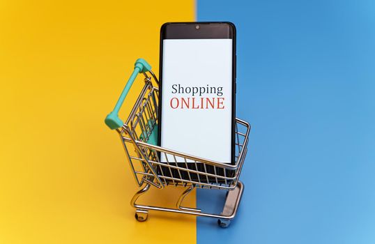 Shopping cart with smartphone. Online shopping concept.